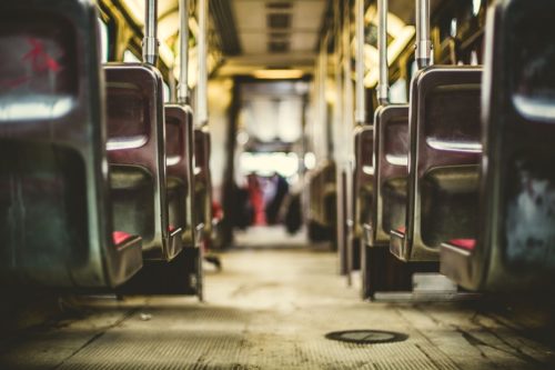 View of the interior of an empty bus, showing rows of seats on either side and a central aisle. The perspective focuses on the aisle leading to the front, with a slightly blurred background—a peaceful scene far removed from bustling days or reminders of bus accidents.